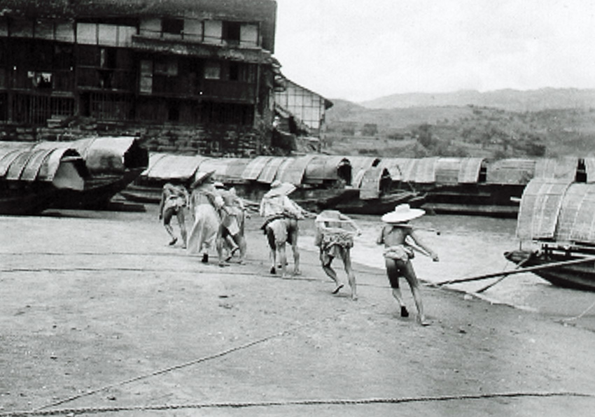 A group of Chinese men pull a sampan along the inlet or river way